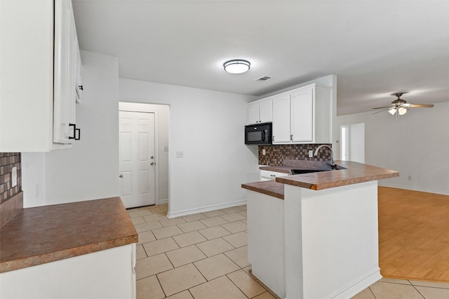 91 Pecan Dr, Pottsboro, TX 75076 - kitchen featuring a sink, black microwave, a peninsula, light tile patterned flooring, and white cabinets