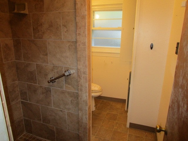 bathroom with tiled shower, toilet, and tile patterned floors