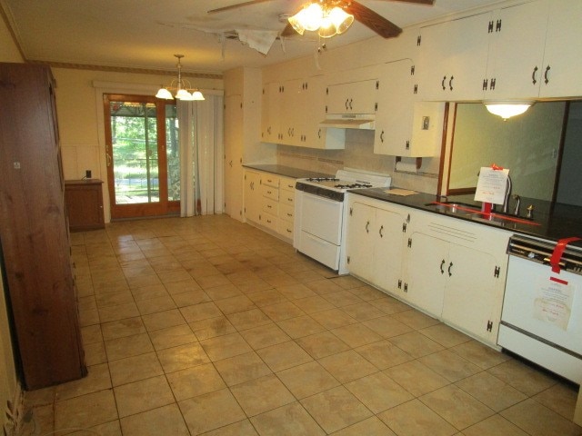 kitchen with white cabinets, hanging light fixtures, ceiling fan with notable chandelier, white appliances, and sink