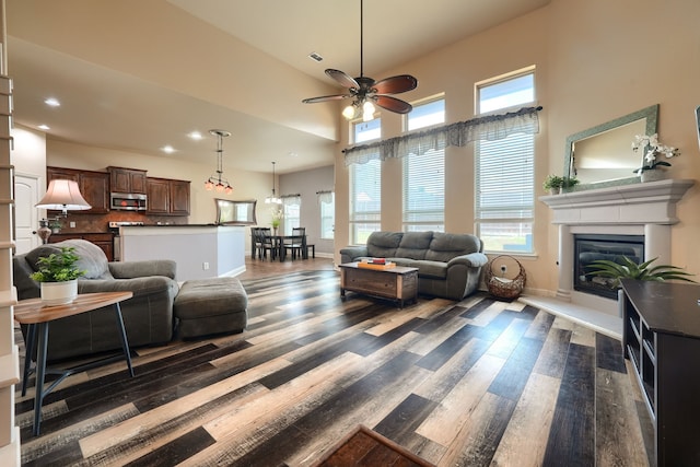 living room featuring a towering ceiling, dark wood-type flooring, and ceiling fan