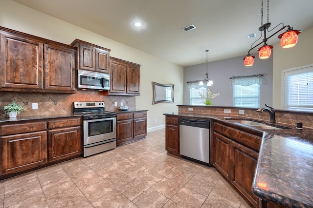 kitchen featuring tasteful backsplash, dark brown cabinets, stainless steel appliances, sink, and decorative light fixtures