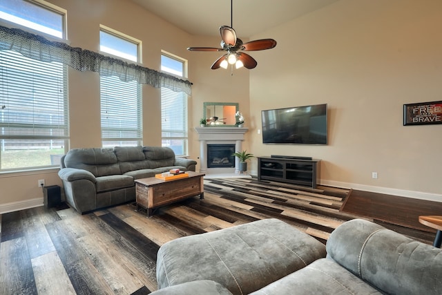 living room featuring a towering ceiling, wood-type flooring, and a wealth of natural light