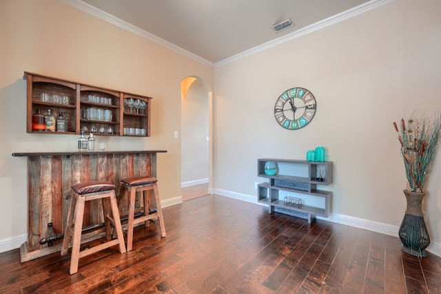 bar featuring ornamental molding and dark hardwood / wood-style flooring