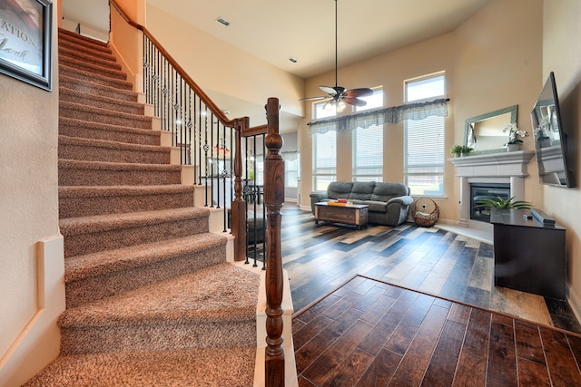 stairs with a wealth of natural light, hardwood / wood-style floors, a high ceiling, and ceiling fan