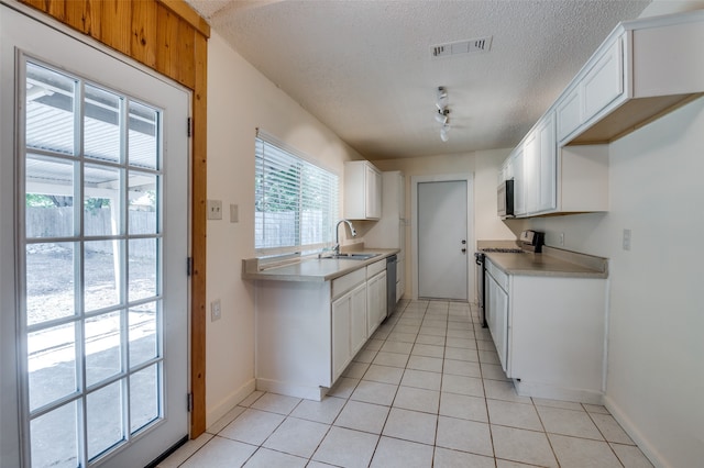 kitchen with a textured ceiling, sink, appliances with stainless steel finishes, and white cabinets