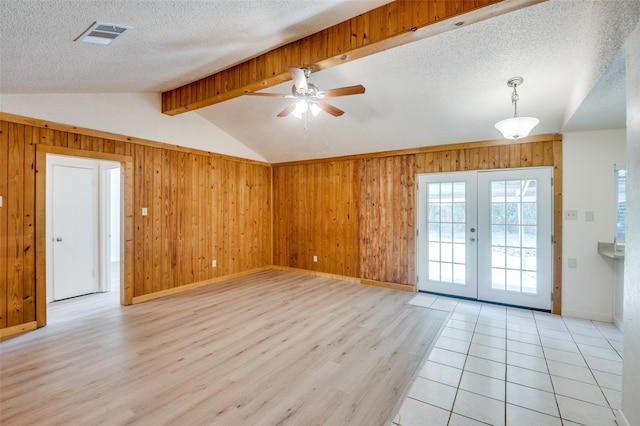 interior space with a textured ceiling, ceiling fan, light wood-type flooring, and wooden walls