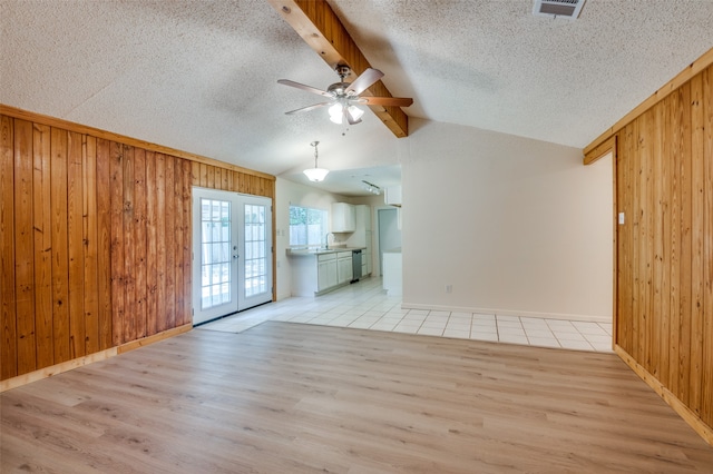 spare room with light hardwood / wood-style flooring, ceiling fan, wooden walls, and french doors