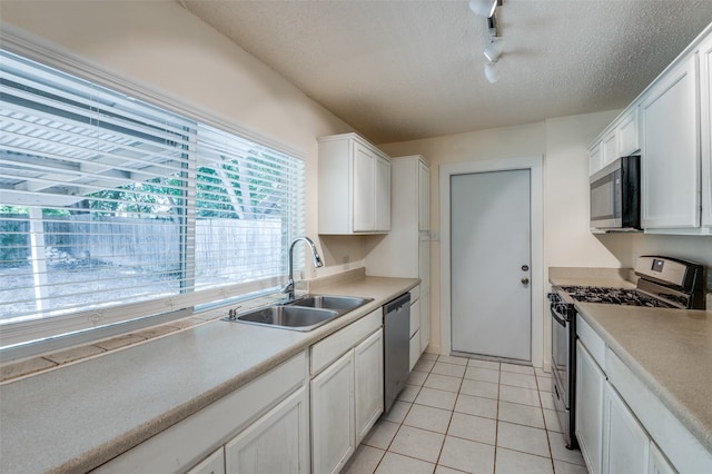 kitchen featuring appliances with stainless steel finishes, a textured ceiling, white cabinetry, and sink