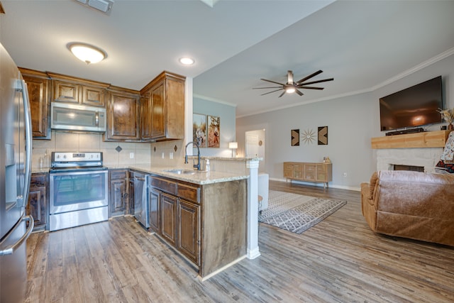 kitchen with backsplash, light stone counters, stainless steel appliances, sink, and ceiling fan