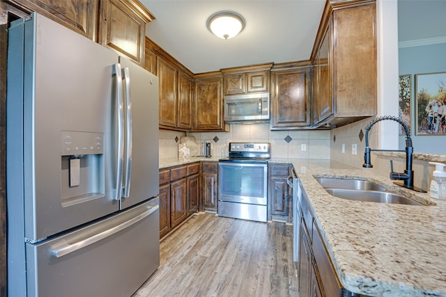 kitchen featuring light hardwood / wood-style flooring, backsplash, sink, light stone countertops, and appliances with stainless steel finishes