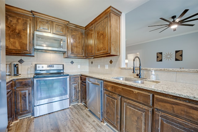 kitchen with light hardwood / wood-style flooring, stainless steel appliances, light stone counters, sink, and ceiling fan