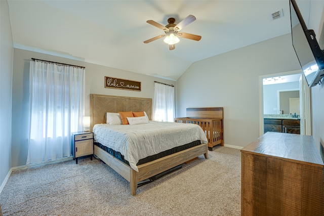 carpeted bedroom with ceiling fan, ensuite bathroom, and vaulted ceiling