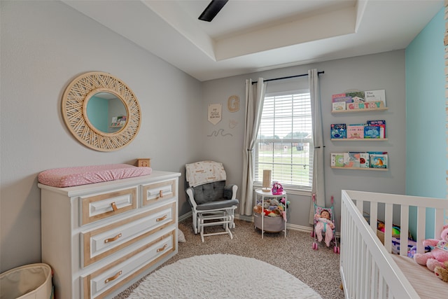 carpeted bedroom with a raised ceiling and ceiling fan