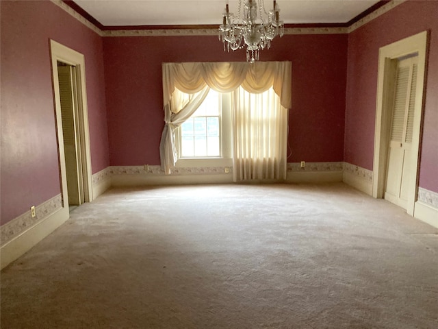 spare room featuring ornamental molding, a notable chandelier, and carpet floors