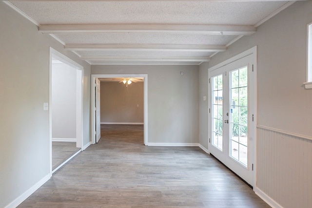 unfurnished room with a textured ceiling, wood-type flooring, beam ceiling, french doors, and ceiling fan