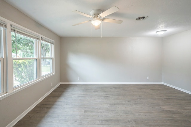 spare room with a textured ceiling, a healthy amount of sunlight, ceiling fan, and hardwood / wood-style floors