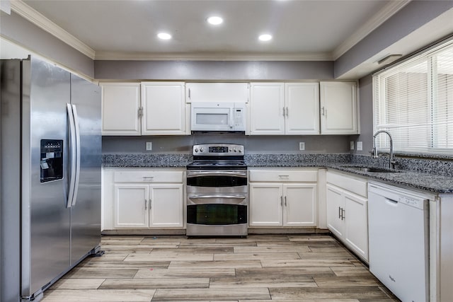 kitchen featuring appliances with stainless steel finishes, dark stone counters, white cabinetry, and sink