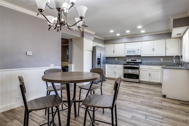 kitchen featuring white cabinets, stainless steel appliances, light wood-type flooring, an inviting chandelier, and sink