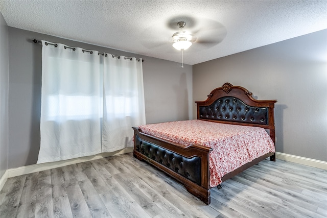 bedroom with light wood-type flooring, ceiling fan, and a textured ceiling