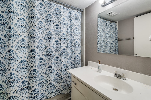 bathroom with a textured ceiling, vanity, and curtained shower