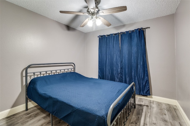 bedroom featuring wood-type flooring, ceiling fan, and a textured ceiling