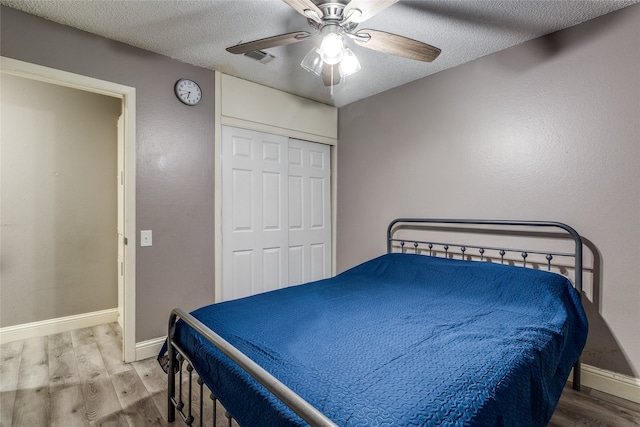 bedroom featuring ceiling fan, a textured ceiling, a closet, and wood-type flooring