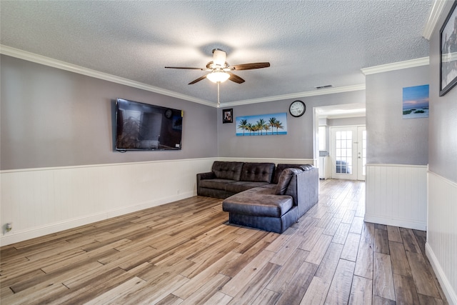 living room featuring ceiling fan, a textured ceiling, light hardwood / wood-style flooring, and crown molding