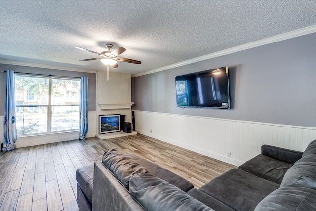 living room with ceiling fan, hardwood / wood-style flooring, a fireplace, and a textured ceiling