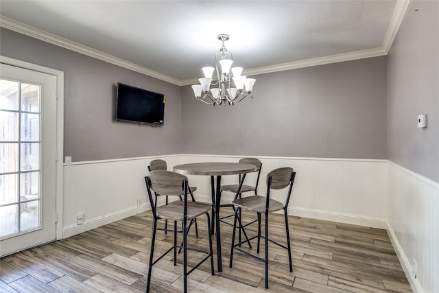 dining area with light wood-type flooring, crown molding, and a chandelier