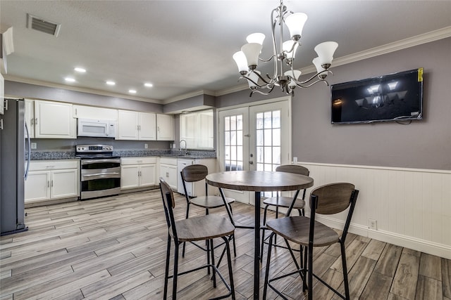 dining space featuring crown molding, an inviting chandelier, light hardwood / wood-style flooring, and sink