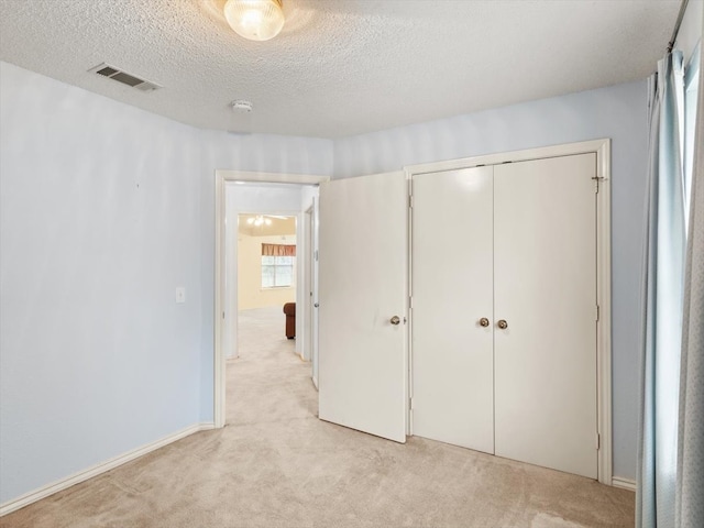 unfurnished bedroom with a closet, light carpet, and a textured ceiling