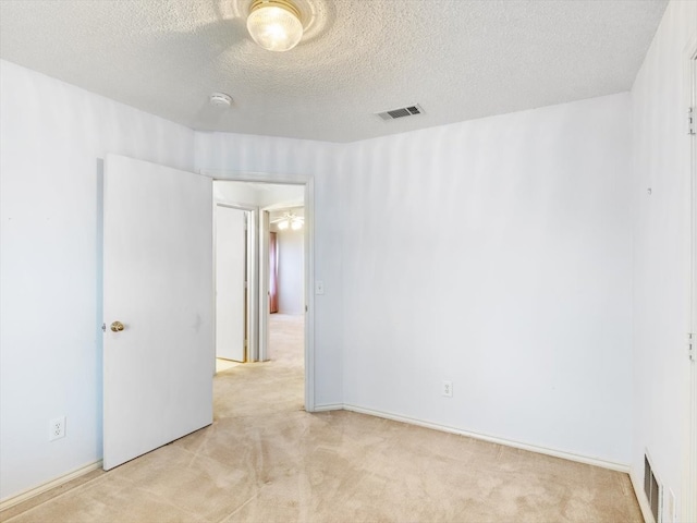 spare room featuring light carpet and a textured ceiling