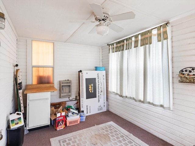 playroom with wood walls, a healthy amount of sunlight, dark carpet, and ceiling fan