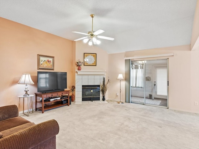 carpeted living room featuring a textured ceiling, lofted ceiling, ceiling fan, and a tile fireplace