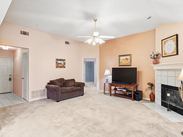 living room featuring light colored carpet, ceiling fan, a tile fireplace, and vaulted ceiling