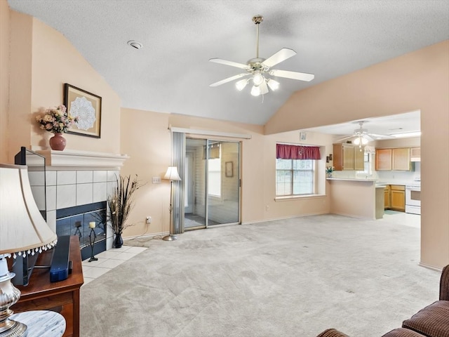 carpeted living room with a textured ceiling, ceiling fan, vaulted ceiling, and a fireplace