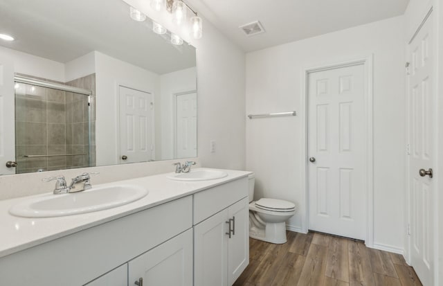 bathroom featuring vanity, toilet, wood-type flooring, and walk in shower