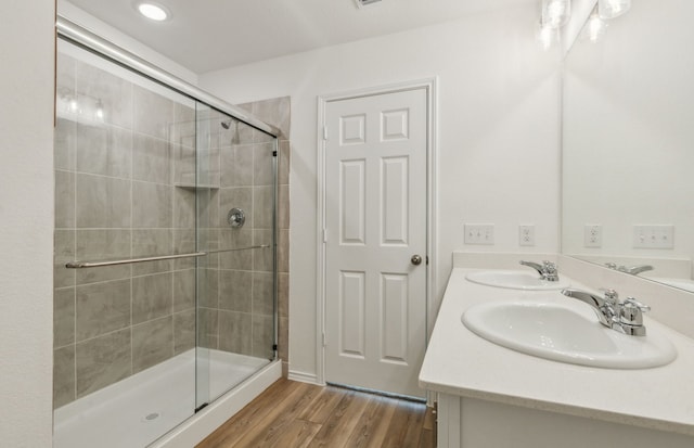 bathroom with hardwood / wood-style floors, vanity, and a shower with shower door