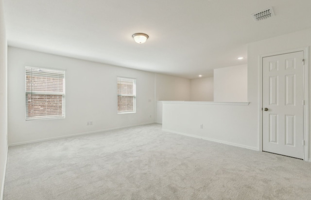 unfurnished room with light colored carpet and plenty of natural light