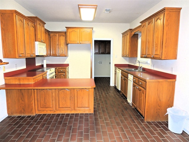 kitchen featuring white appliances, kitchen peninsula, and sink