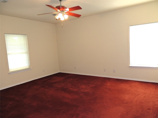 carpeted empty room with ceiling fan and plenty of natural light