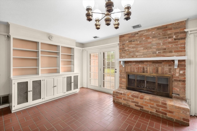 unfurnished living room featuring an inviting chandelier and a brick fireplace