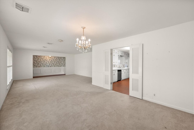 spare room with carpet flooring and a chandelier