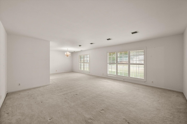 carpeted spare room with a chandelier