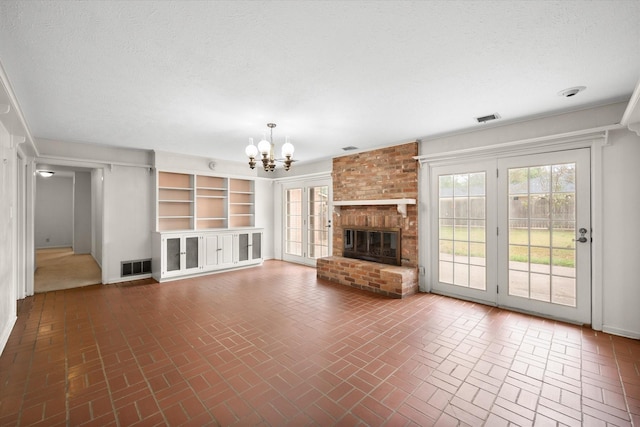 unfurnished living room featuring a fireplace, a textured ceiling, and an inviting chandelier