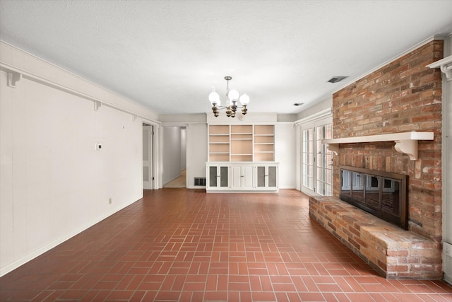 unfurnished living room with a chandelier, a textured ceiling, and a brick fireplace