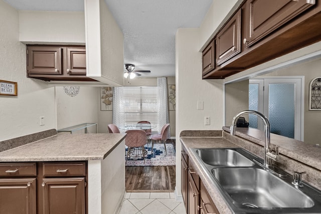 kitchen with light hardwood / wood-style floors, sink, kitchen peninsula, ceiling fan, and a textured ceiling