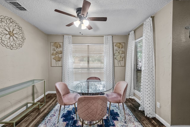 dining area featuring dark wood-type flooring, a textured ceiling, and ceiling fan