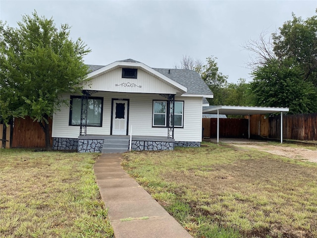 bungalow with a porch, fence, driveway, roof with shingles, and a front lawn