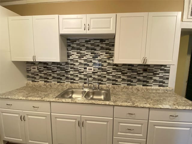 kitchen featuring tasteful backsplash, a sink, and white cabinets